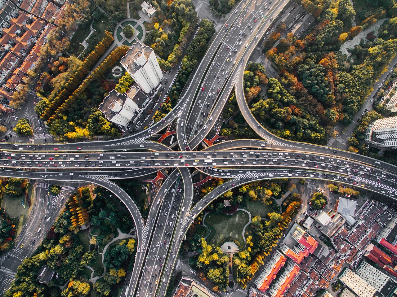 Aerial view of a multi-level freeway interchange surrounded by trees and city neighborhoods.